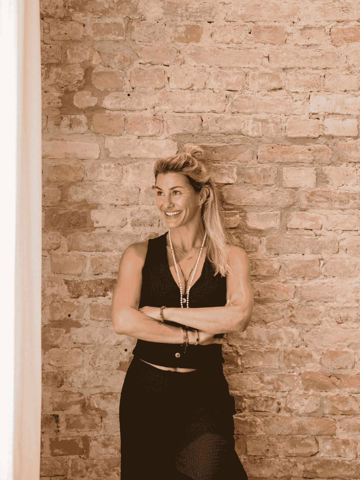 Dominique Scharax, lachend vor Backsteinwand